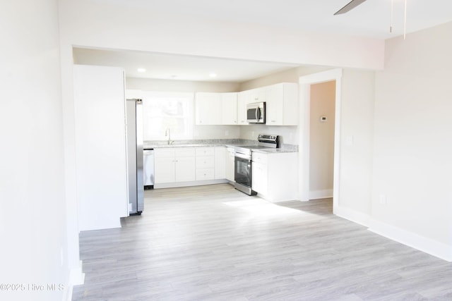 kitchen featuring white cabinets, appliances with stainless steel finishes, light hardwood / wood-style floors, and sink