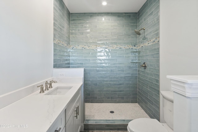 bathroom with a tile shower, vanity, and toilet