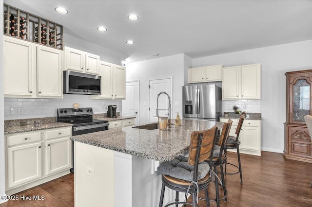 kitchen featuring appliances with stainless steel finishes, dark wood-style flooring, a sink, and stone counters