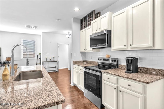 kitchen with visible vents, dark wood finished floors, decorative backsplash, stainless steel appliances, and a sink