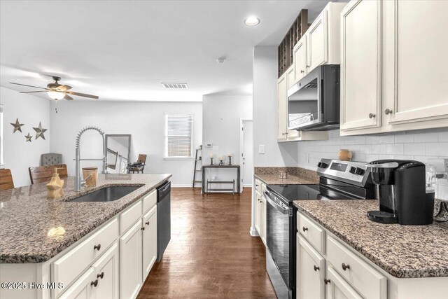 kitchen with stainless steel appliances, dark wood-style flooring, a sink, visible vents, and backsplash