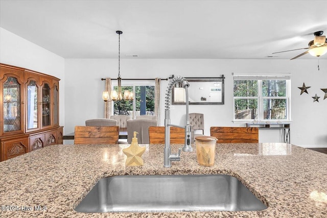 kitchen featuring a wealth of natural light, visible vents, a sink, and light stone countertops