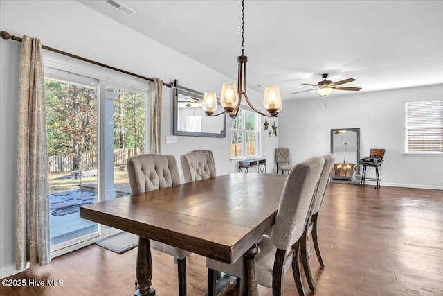 dining area featuring ceiling fan with notable chandelier, visible vents, baseboards, and wood finished floors