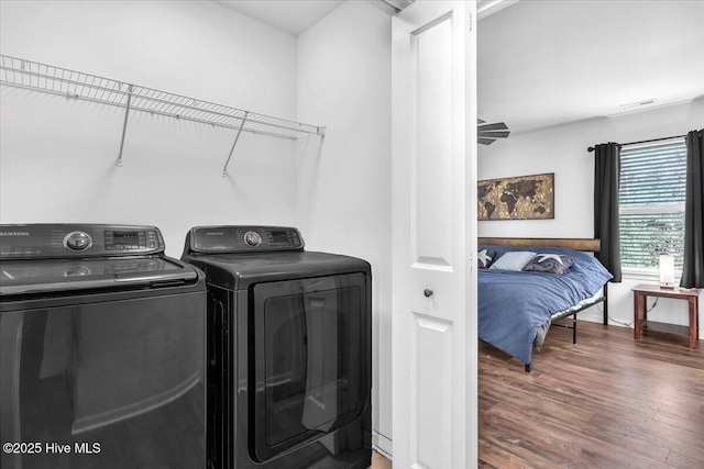 laundry area with laundry area, visible vents, washer and dryer, and wood finished floors