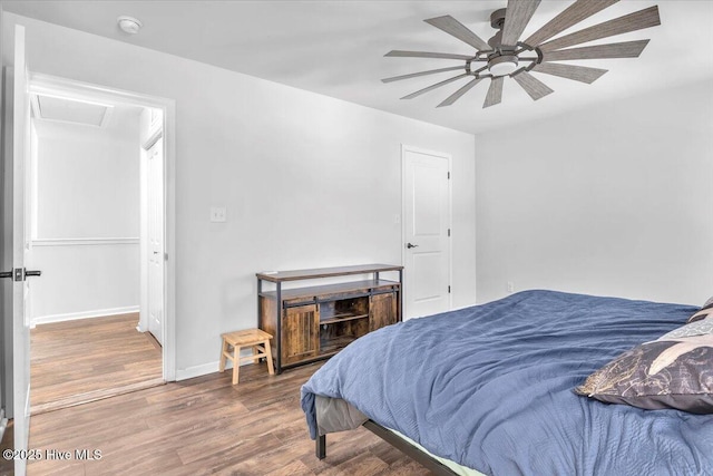 bedroom featuring ceiling fan, wood finished floors, attic access, and baseboards