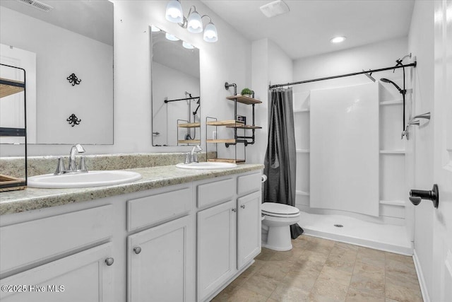 full bathroom with a sink, a shower stall, toilet, and double vanity