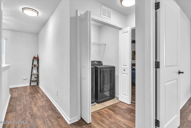 washroom featuring washing machine and dryer, laundry area, visible vents, and wood finished floors