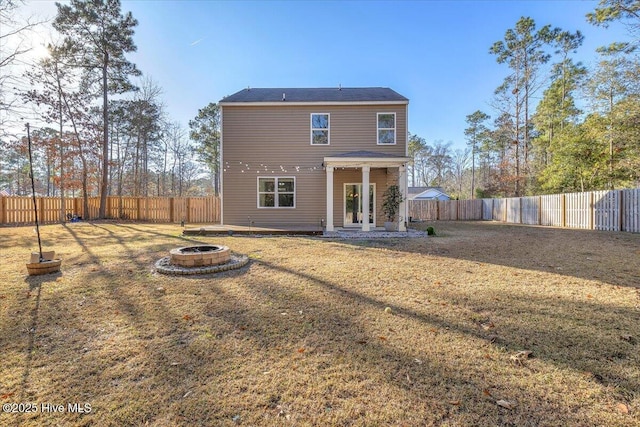 rear view of house featuring a fire pit, a lawn, and a fenced backyard