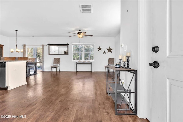 interior space featuring visible vents, a barn door, dark wood-type flooring, baseboards, and ceiling fan with notable chandelier