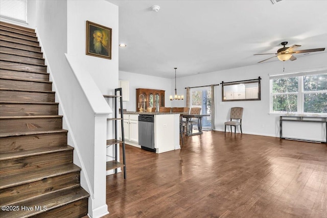 interior space with dishwasher, a kitchen breakfast bar, dark wood-style flooring, white cabinetry, and ceiling fan with notable chandelier