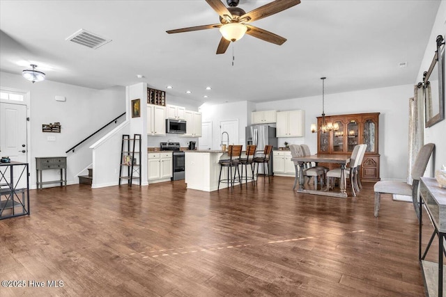 living area featuring visible vents, dark wood-style floors, stairs, ceiling fan with notable chandelier, and recessed lighting