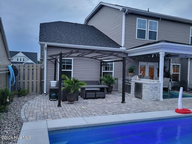 rear view of house featuring a fenced in pool, a patio, and an outdoor kitchen