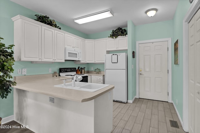 kitchen featuring white cabinets, white appliances, kitchen peninsula, and sink