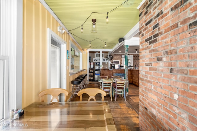 dining room with wood-type flooring and brick wall