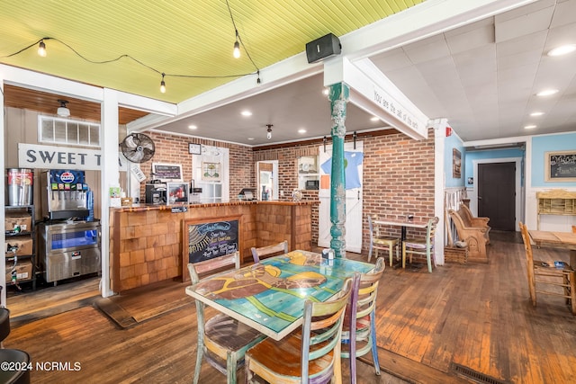 dining room with crown molding, dark wood-type flooring, and brick wall