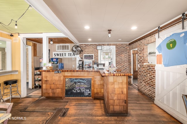 bar with wooden counters, brick wall, crown molding, a barn door, and dark hardwood / wood-style floors