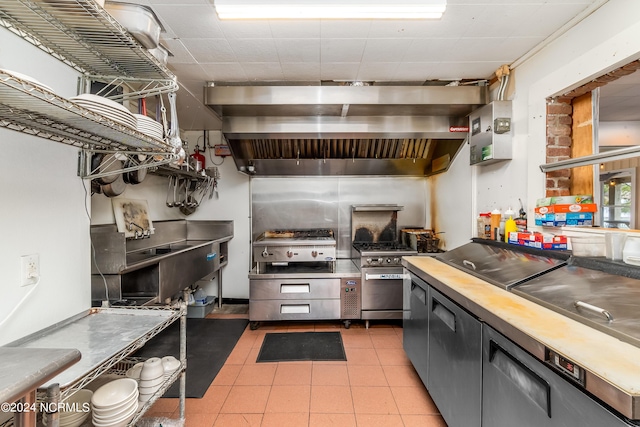 kitchen featuring stainless steel stove, light tile patterned floors, and ventilation hood