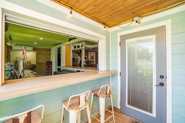 exterior space featuring a wall unit AC, wood walls, wooden ceiling, and hardwood / wood-style flooring