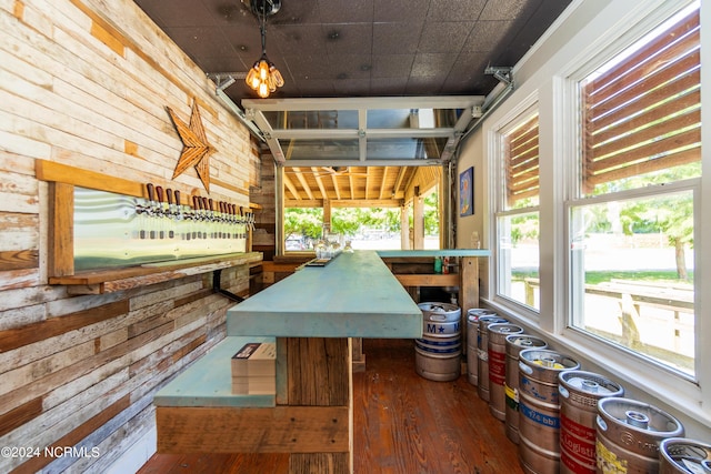 interior space with a wealth of natural light, wood walls, and dark wood-type flooring