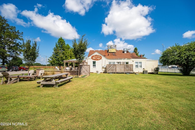 rear view of property featuring a lawn and a wooden deck