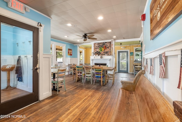 dining area featuring ceiling fan, a large fireplace, wood-type flooring, and cooling unit