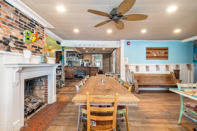 dining space featuring hardwood / wood-style flooring, ceiling fan, ornamental molding, and brick wall