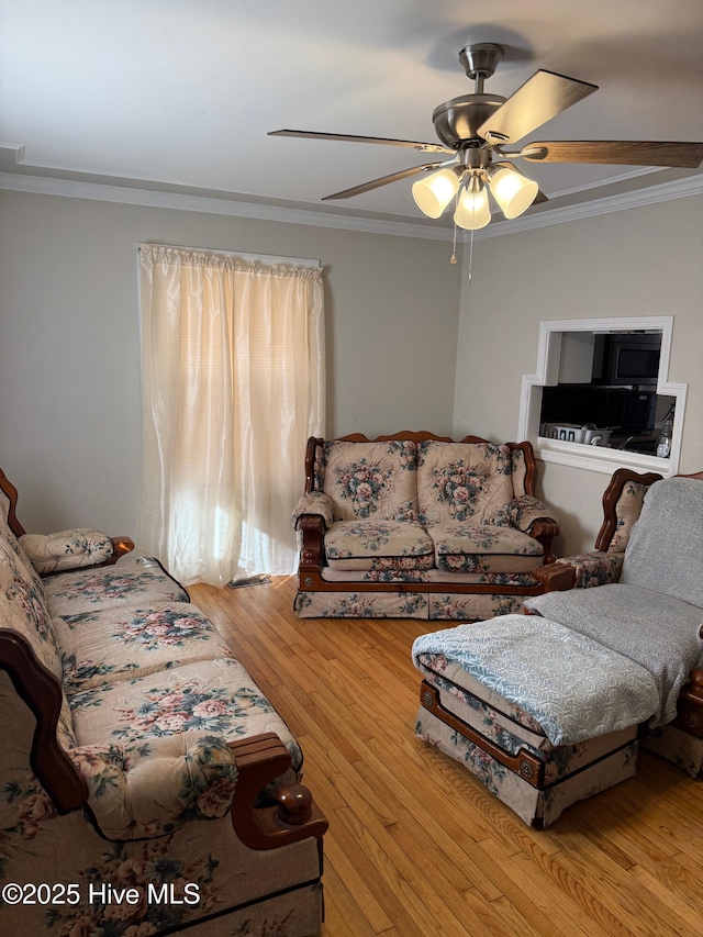 living room with ornamental molding, light hardwood / wood-style floors, and ceiling fan