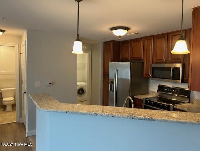 kitchen featuring kitchen peninsula, washer / dryer, stainless steel appliances, and hanging light fixtures