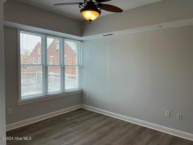 unfurnished room with ceiling fan, dark wood-type flooring, and a wealth of natural light