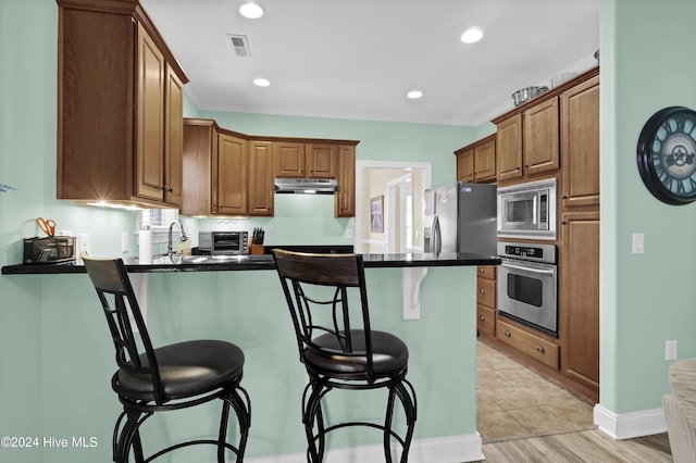 kitchen featuring a breakfast bar, sink, kitchen peninsula, and stainless steel appliances