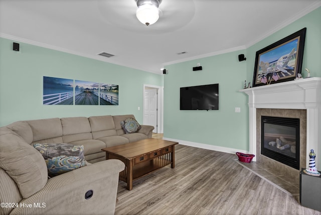 living room featuring crown molding, a fireplace, ceiling fan, and hardwood / wood-style flooring