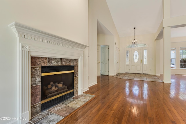 3882 White Blossom Cir, Southport, NC 28461 - entryway featuring a notable chandelier, baseboards, a tiled fireplace, hardwood / wood-style floors, and high vaulted ceiling