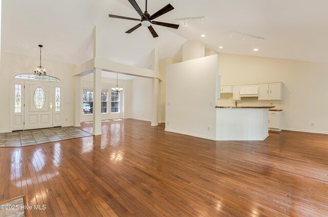 3882 White Blossom Cir, Southport, NC 28461 - unfurnished living room with high vaulted ceiling, wood-type flooring, baseboards, and track lighting