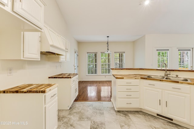 3882 White Blossom Cir, Southport, NC 28461 - kitchen with white cabinetry, butcher block counters, visible vents, a sink, and hanging light fixtures