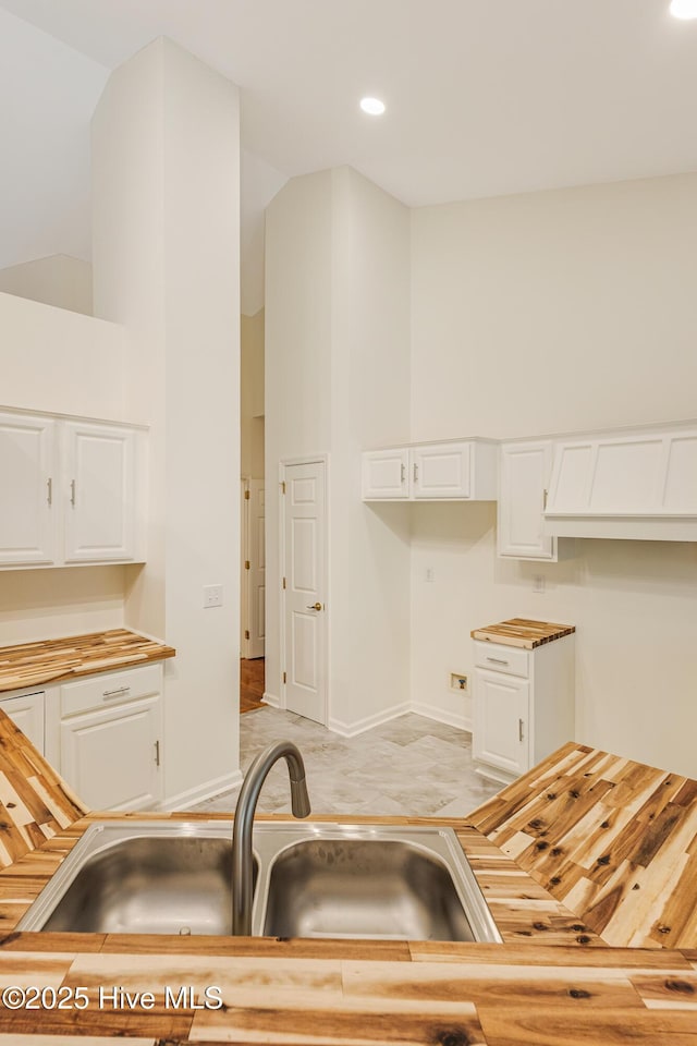 3882 White Blossom Cir, Southport, NC 28461 - kitchen featuring butcher block countertops, baseboards, a sink, and white cabinets