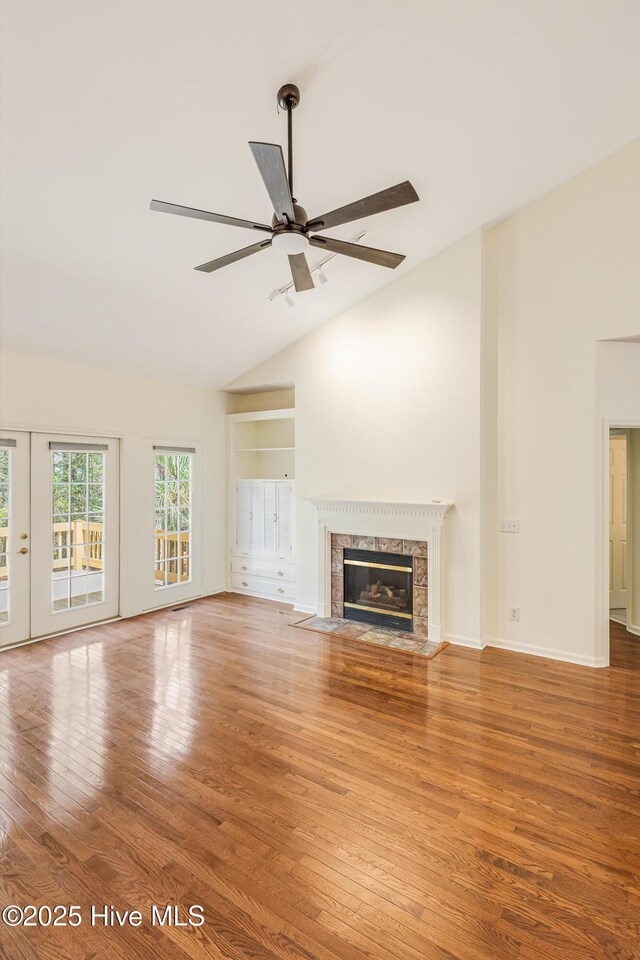 3882 White Blossom Cir, Southport, NC 28461 - unfurnished living room with high vaulted ceiling, a fireplace, ceiling fan, and wood finished floors