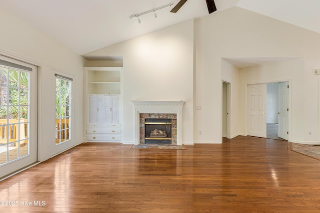 3882 White Blossom Cir, Southport, NC 28461 - unfurnished living room featuring a high end fireplace, track lighting, wood finished floors, and lofted ceiling