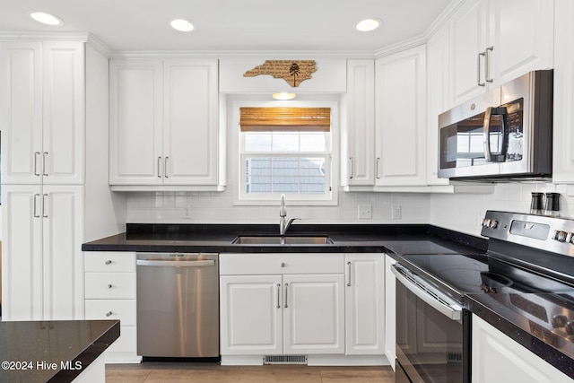 kitchen with decorative backsplash, white cabinetry, sink, and appliances with stainless steel finishes