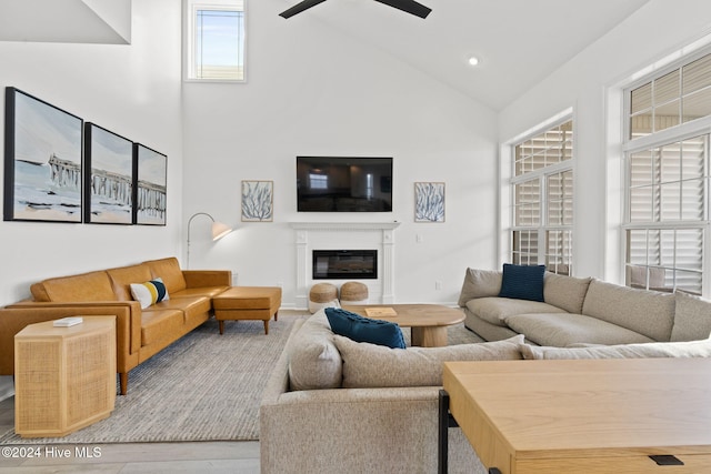 living room featuring ceiling fan, high vaulted ceiling, and light hardwood / wood-style flooring