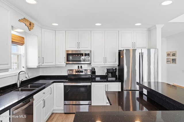 kitchen with white cabinetry, sink, backsplash, dark stone countertops, and appliances with stainless steel finishes