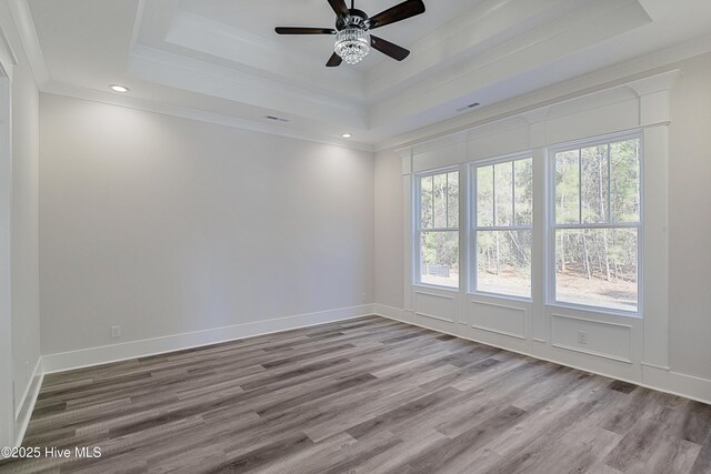 unfurnished room featuring hardwood / wood-style flooring, ceiling fan, a raised ceiling, and crown molding