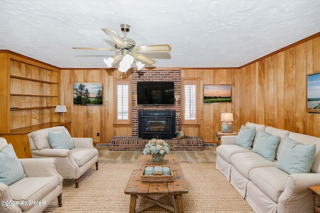 living room with ceiling fan, a fireplace, wood walls, and a textured ceiling