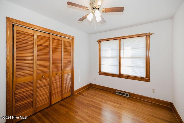 unfurnished bedroom with ceiling fan, a closet, and hardwood / wood-style flooring