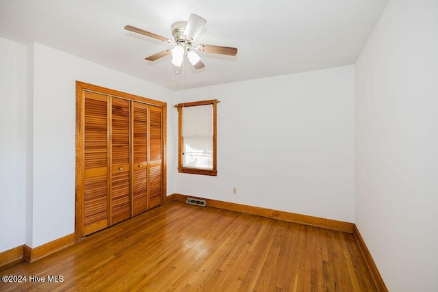 unfurnished bedroom with ceiling fan, wood-type flooring, and a closet