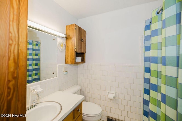 bathroom featuring vanity, toilet, and tile walls