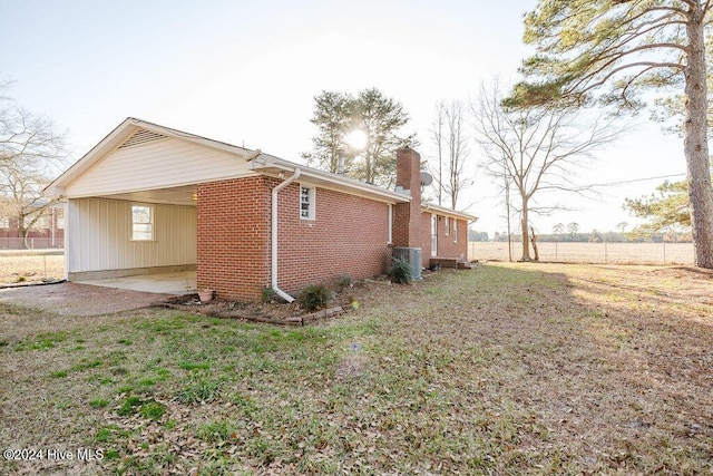 view of side of home featuring a carport, a lawn, and central AC