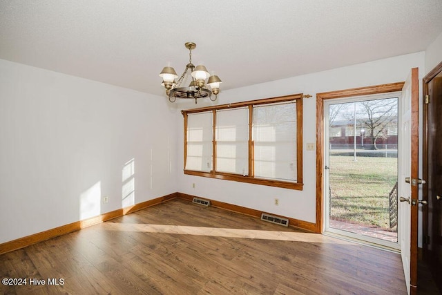 unfurnished dining area with wood-type flooring and a notable chandelier