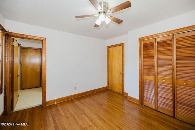 unfurnished bedroom with ceiling fan, a closet, and wood-type flooring