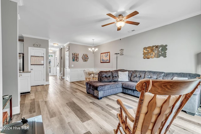 living area with light wood-style flooring, ceiling fan with notable chandelier, visible vents, wainscoting, and crown molding