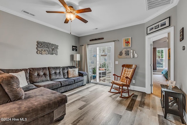 living room with ceiling fan, light wood finished floors, visible vents, and crown molding